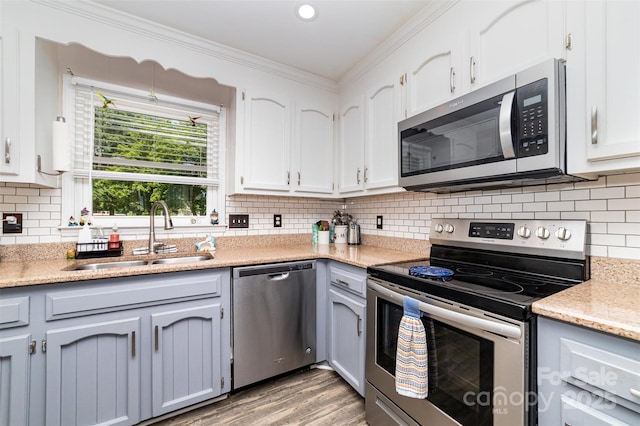 2401 Hoffman St, Gastonia, NC 28054 - kitchen featuring appliances with stainless steel finishes, a sink, ornamental molding, light wood-style floors, and white cabinets
