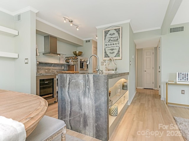 212 W 10th St Unit 3, Charlotte, NC 28202 - kitchen with wall chimney range hood, light wood-style floors, a sink, beverage cooler, and crown molding
