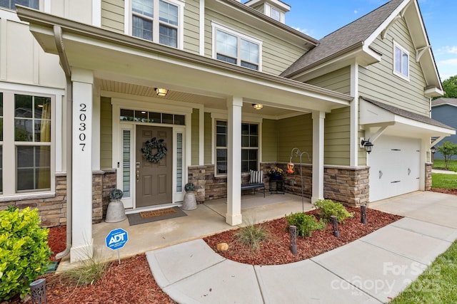 20307 Creek Bend Edge Ct Unit 10, Matthews, NC 28105 - property entrance featuring a porch, stone siding, a garage, and roof with shingles