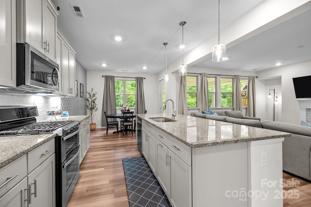 20307 Creek Bend Edge Ct Unit 10, Matthews, NC 28105 - kitchen with stainless steel appliances, open floor plan, light wood-style flooring, a center island with sink, and tasteful backsplash
