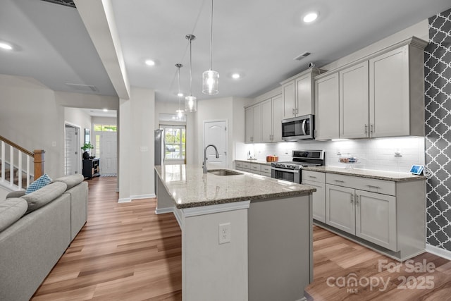 20307 Creek Bend Edge Ct Unit 10, Matthews, NC 28105 - kitchen featuring stainless steel appliances, light wood-style flooring, a kitchen island with sink, open floor plan, and light stone countertops