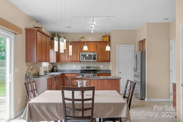 6104 Follow The Trl, Indian Trail, NC 28079 - kitchen featuring stainless steel appliances, track lighting, a sink, brown cabinets, and tasteful backsplash