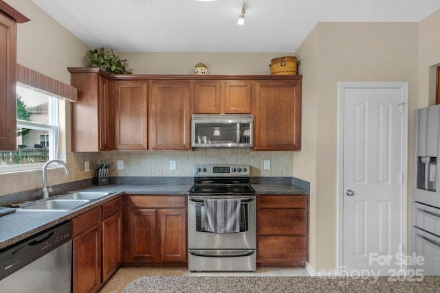 6104 Follow The Trl, Indian Trail, NC 28079 - kitchen featuring appliances with stainless steel finishes, a sink, backsplash, brown cabinets, and light tile patterned flooring