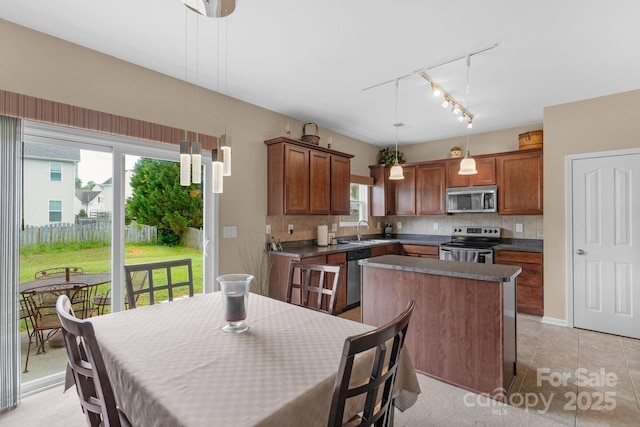 6104 Follow The Trl, Indian Trail, NC 28079 - kitchen featuring appliances with stainless steel finishes, a sink, a kitchen island, rail lighting, and decorative backsplash