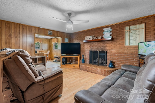 2401 Hillside Dr, Newton, NC 28658 - living area featuring wood finished floors, a brick fireplace, wooden walls, ceiling fan, and a textured ceiling