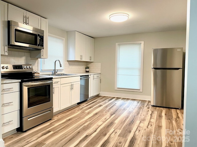 216 N Vance St, Gastonia, NC 28052 - kitchen with appliances with stainless steel finishes, a sink, light wood finished floors, tasteful backsplash, and white cabinets