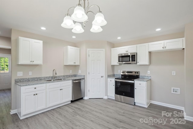 528 S Caldwell St, Salisbury, NC 28144 - kitchen featuring stainless steel appliances, a chandelier, light wood-type flooring, white cabinetry, and light stone countertops