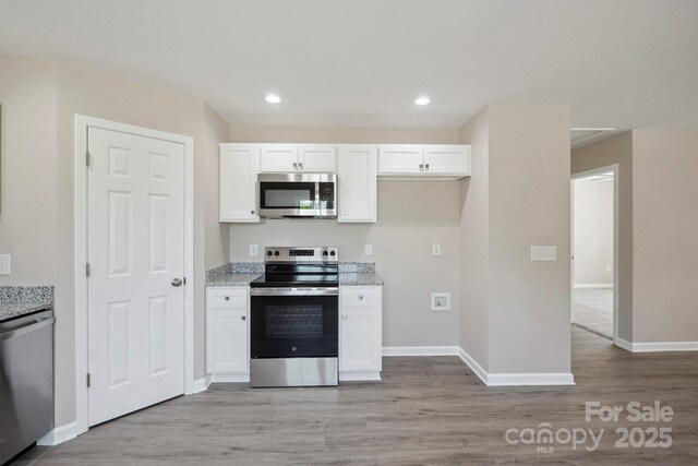 528 S Caldwell St, Salisbury, NC 28144 - kitchen with appliances with stainless steel finishes, light wood-style floors, white cabinets, light stone counters, and recessed lighting