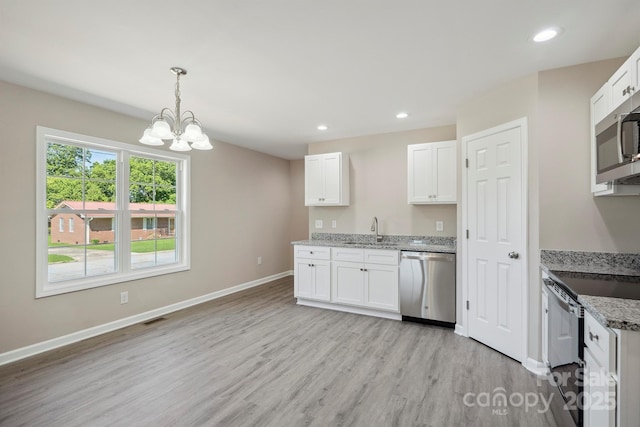 528 S Caldwell St, Salisbury, NC 28144 - kitchen with appliances with stainless steel finishes, light wood-style flooring, a chandelier, white cabinets, and light stone countertops