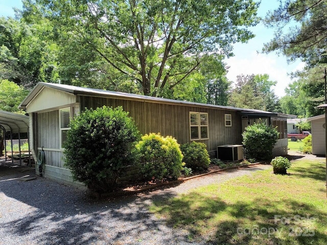 view of property exterior with central AC, a detached carport, and a yard