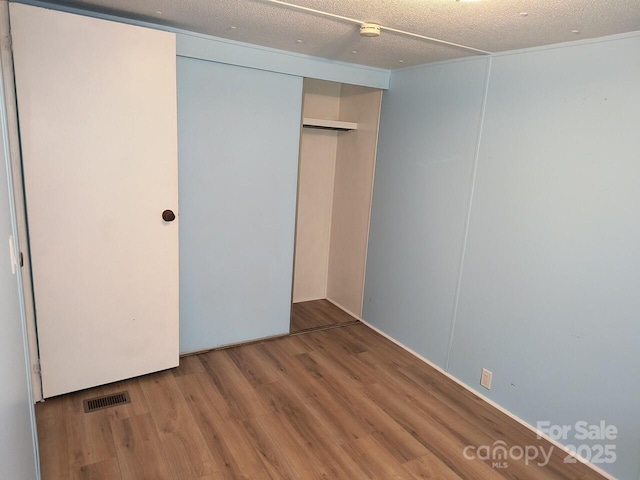 unfurnished bedroom featuring wood finished floors, a closet, and a textured ceiling