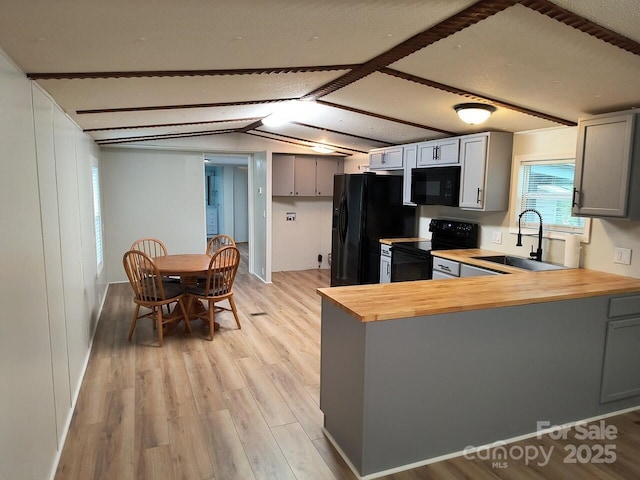 kitchen with black appliances, a sink, wood counters, gray cabinets, and light wood-style flooring