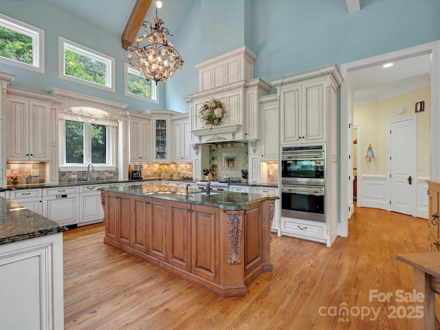 6742 Charlotte Hwy, York, SC 29745 - kitchen featuring double oven, high vaulted ceiling, a chandelier, decorative backsplash, and dark stone countertops