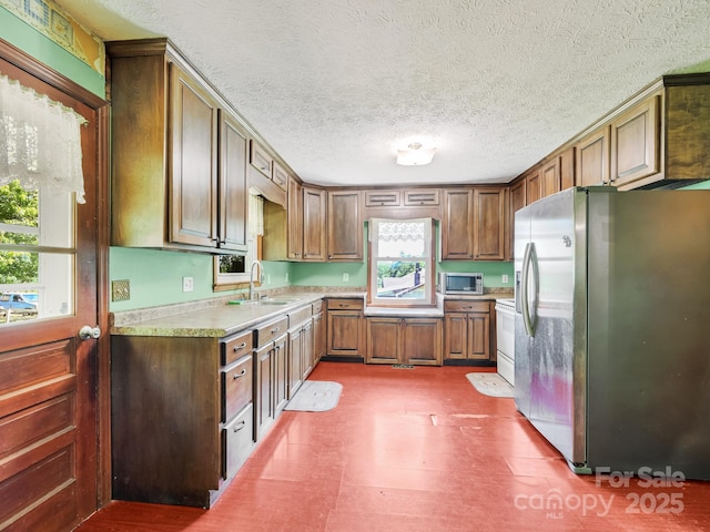 522 Bailey Mountain Rd, Mars Hill, NC 28754 - kitchen with appliances with stainless steel finishes, a sink, light countertops, a textured ceiling, and brown cabinets