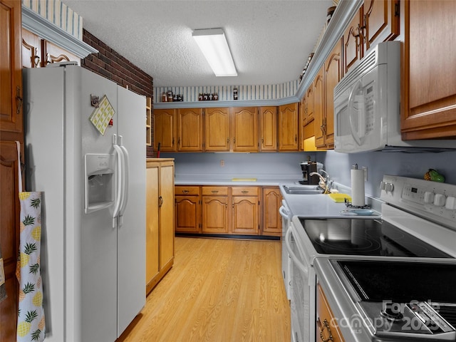 6 Woodley Ave, Asheville, NC 28804 - kitchen with white appliances, light wood finished floors, a textured ceiling, brown cabinetry, and a sink