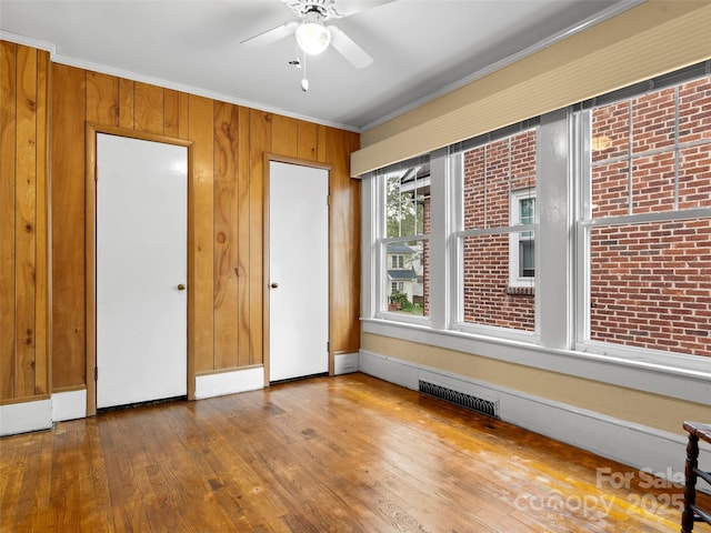 6 Woodley Ave, Asheville, NC 28804 - unfurnished bedroom with crown molding, wood-type flooring, wood walls, and ceiling fan
