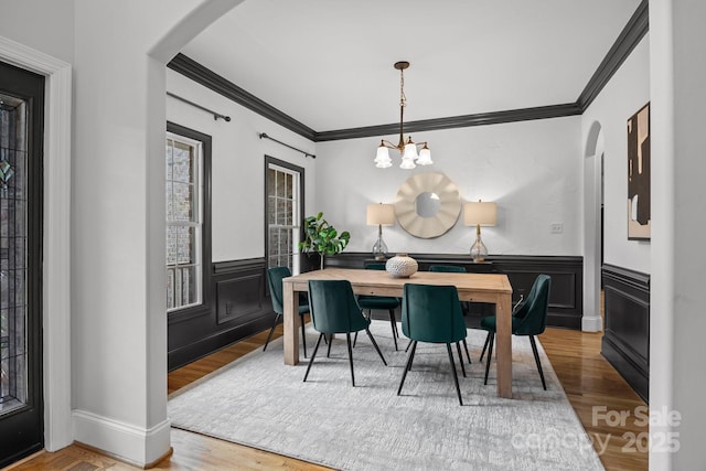 389 Ponderosa Cir, Mooresville, NC 28117 - dining area featuring arched walkways, crown molding, wood finished floors, a chandelier, and a wainscoted wall