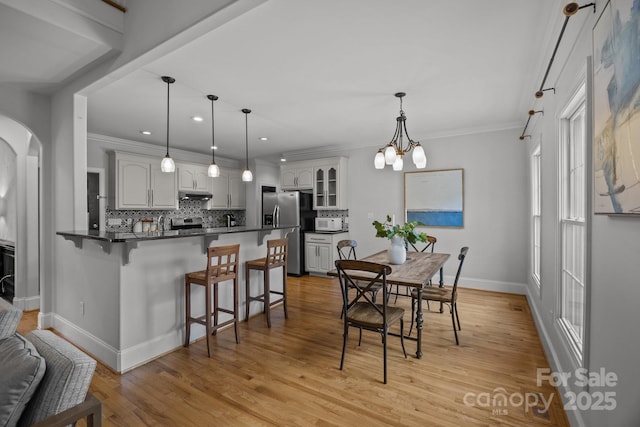 389 Ponderosa Cir, Mooresville, NC 28117 - dining space featuring baseboards, arched walkways, ornamental molding, recessed lighting, and light wood-style flooring