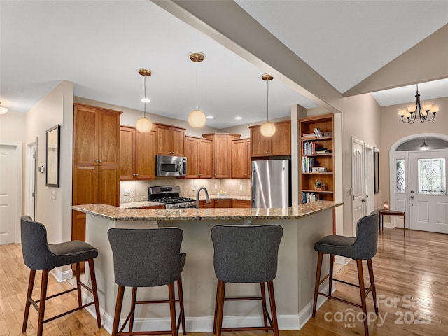 4 Alsatian Ln, Asheville, NC 28805 - kitchen featuring stainless steel appliances, brown cabinetry, backsplash, and light stone countertops