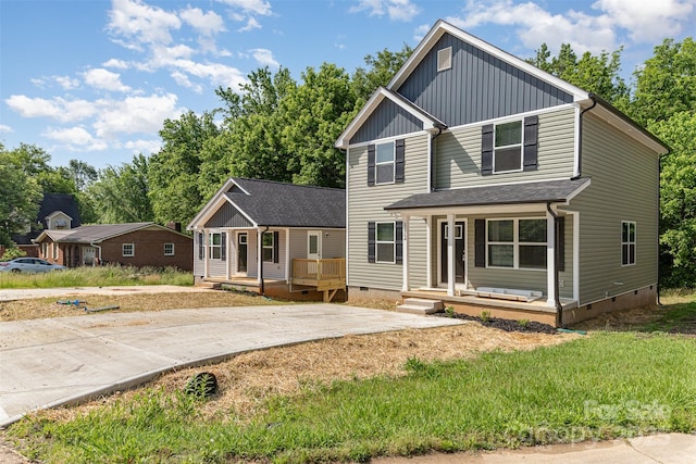 view of front facade featuring crawl space, covered porch, board and batten siding, and a front yard