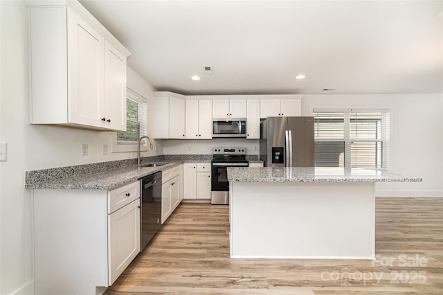 kitchen with stainless steel appliances, a sink, light wood-style floors, white cabinets, and recessed lighting