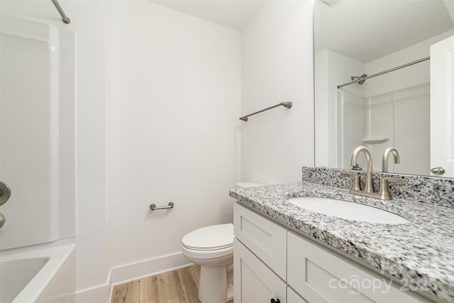 bathroom with wood finished floors, baseboards, toilet, vanity, and shower / tub combination