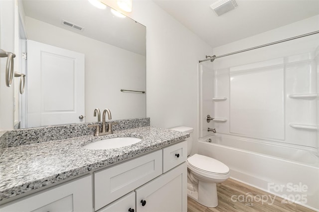 bathroom featuring wood finished floors, toilet, vanity, and washtub / shower combination
