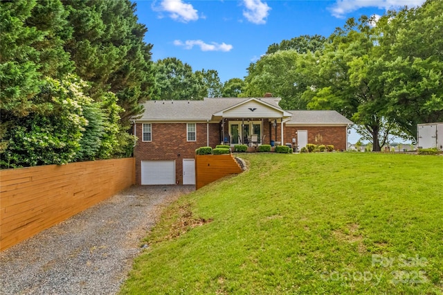 view of front of home with gravel driveway, a garage, brick siding, and a chimney