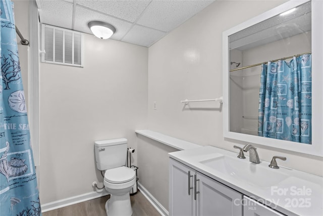 full bath with wood finished floors, toilet, a paneled ceiling, vanity, and baseboards