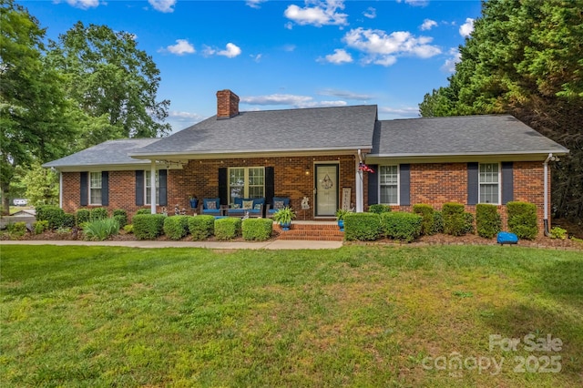 view of front of house featuring a chimney, a front yard, and brick siding