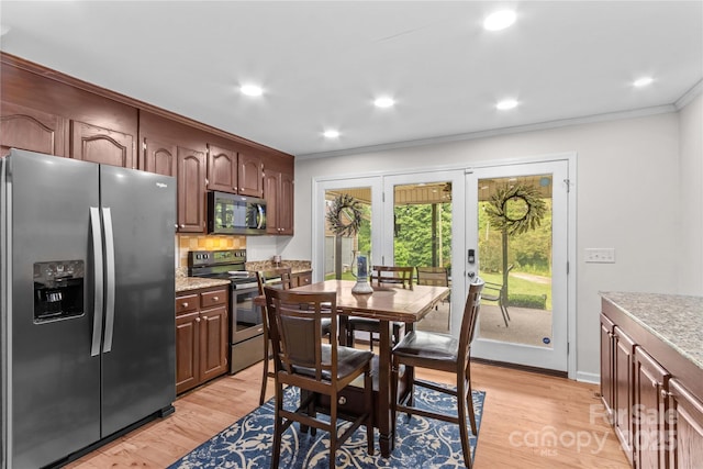 kitchen with stainless steel appliances, french doors, ornamental molding, light countertops, and light wood-type flooring