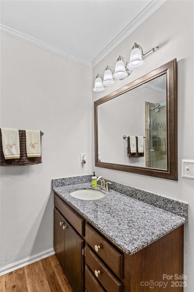 full bathroom featuring crown molding, vanity, wood finished floors, a shower with shower door, and baseboards