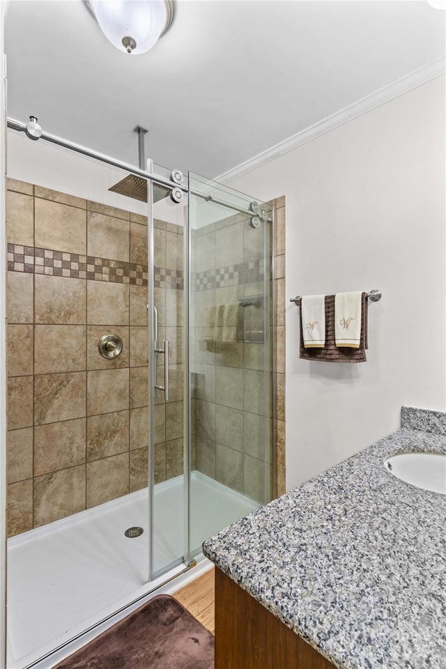 full bathroom featuring a shower stall, crown molding, and a sink