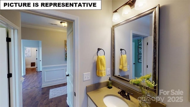 bathroom with crown molding, vanity, a wainscoted wall, and wood finished floors