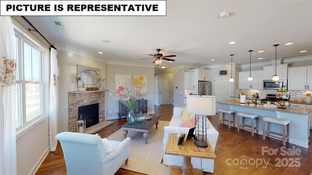 living room with a stone fireplace, baseboards, a ceiling fan, ornamental molding, and recessed lighting
