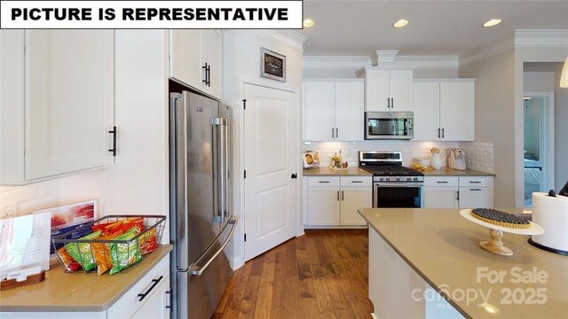 kitchen with appliances with stainless steel finishes, dark wood-style floors, ornamental molding, white cabinets, and tasteful backsplash