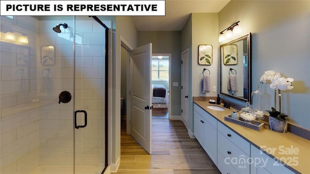ensuite bathroom featuring a stall shower, vanity, and wood finished floors