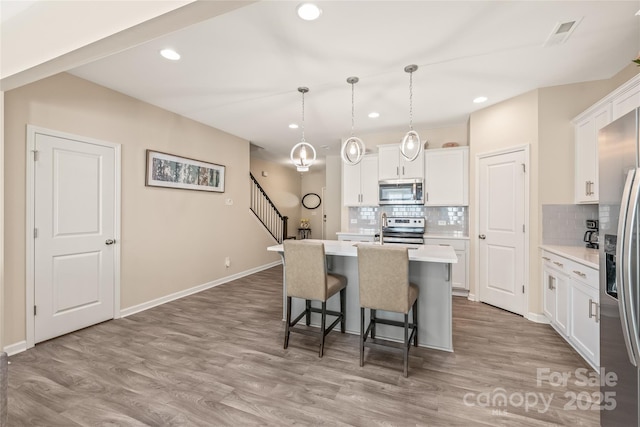 13221 Gadwal Pintail Dr, Charlotte, NC 28262 - kitchen featuring appliances with stainless steel finishes, a breakfast bar, an island with sink, tasteful backsplash, and light countertops