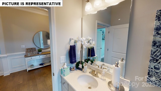 bathroom featuring crown molding, wood finished floors, vanity, and a wainscoted wall