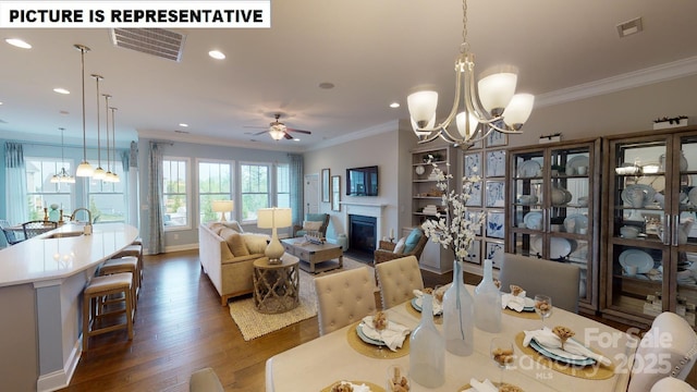 dining space featuring a chandelier, crown molding, dark wood-type flooring, a glass covered fireplace, and recessed lighting