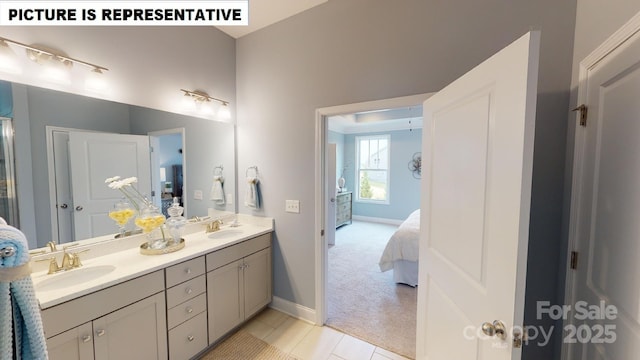 ensuite bathroom with double vanity, baseboards, and tile patterned flooring