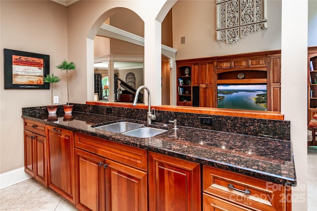 122 Sleepy Cove Trl, Mooresville, NC 28117 - kitchen featuring a sink, dark stone countertops, arched walkways, brown cabinetry, and light tile patterned flooring