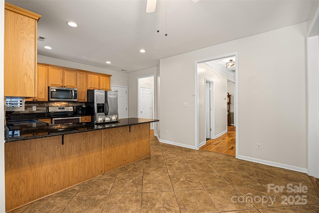 220 Glenville Dr, Fort Mill, SC 29715 - kitchen featuring stainless steel appliances, a peninsula, backsplash, a ceiling fan, and dark stone counters