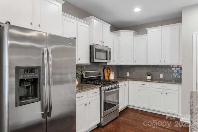 1919 Madeira Cir, Waxhaw, NC 28173 - kitchen with stainless steel appliances, stone countertops, white cabinetry, dark wood-type flooring, and backsplash