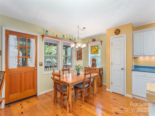 41 Trapper Ln, Waynesville, NC 28785 - dining space featuring a chandelier, baseboards, light wood-type flooring, and a textured ceiling