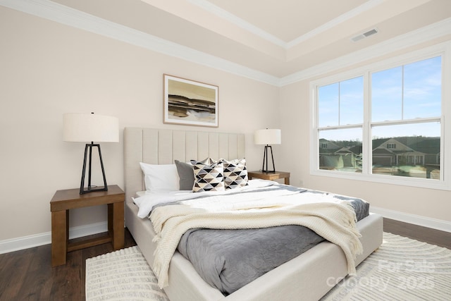 bedroom with dark wood-style flooring, baseboards, ornamental molding, and a raised ceiling