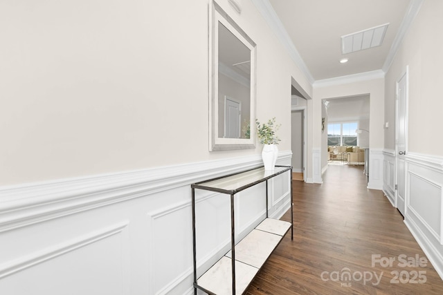 hallway with ornamental molding, dark wood-type flooring, wainscoting, a decorative wall, and recessed lighting