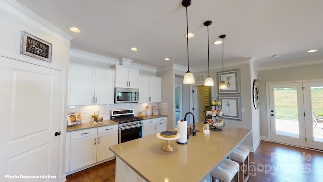 106 Noah Ln, Troutman, NC 28166 - kitchen with appliances with stainless steel finishes, tasteful backsplash, dark wood-type flooring, a kitchen breakfast bar, and white cabinetry