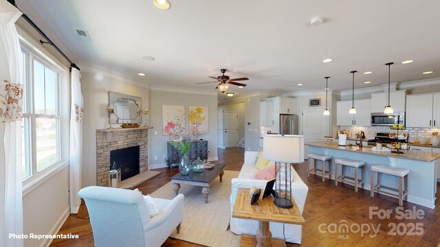 106 Noah Ln, Troutman, NC 28166 - living room with healthy amount of natural light, a stone fireplace, a ceiling fan, ornamental molding, and baseboards