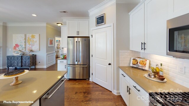 106 Noah Ln, Troutman, NC 28166 - kitchen with appliances with stainless steel finishes, dark wood-type flooring, ornamental molding, tasteful backsplash, and white cabinets